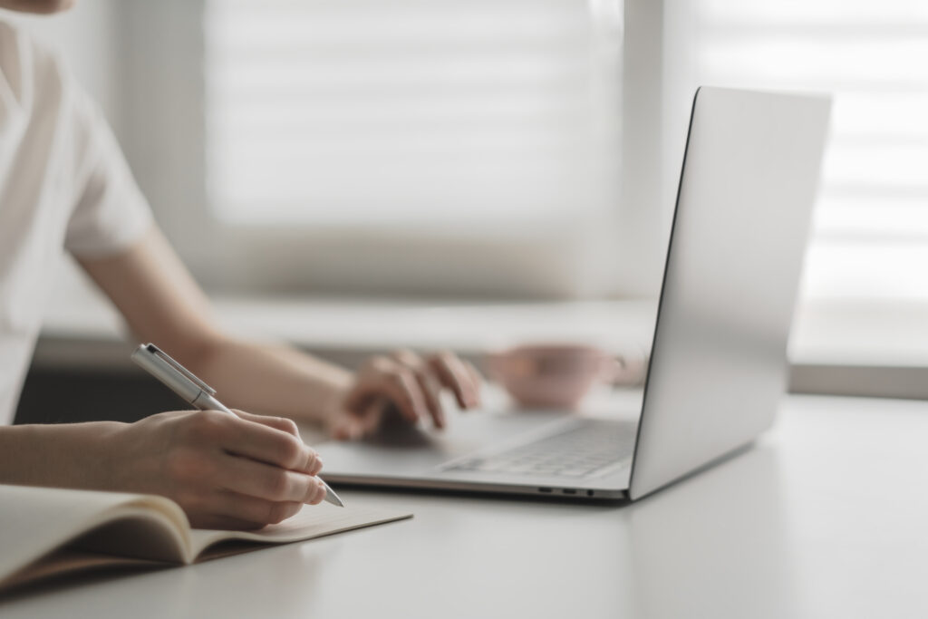 young woman works laptop takes notes notebook young woman works laptop takes notes notebook